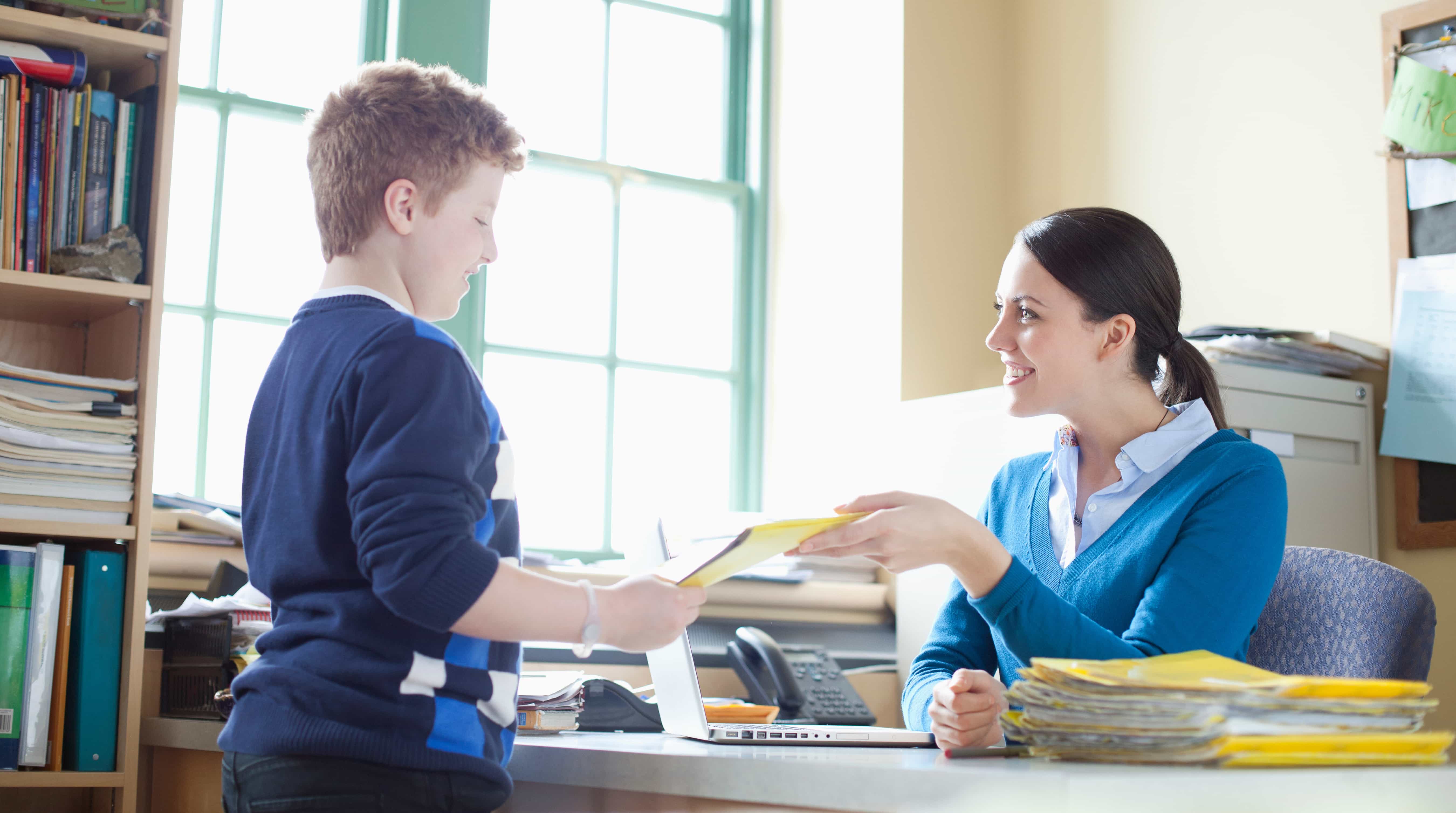 Student handing assessment to teacher.
