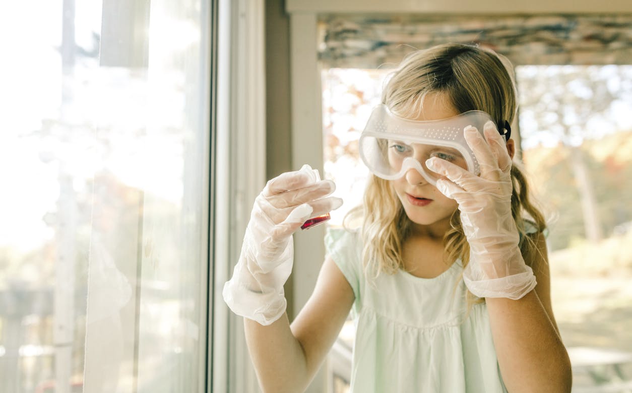 Girl doing science experiment, staring at measuring flask