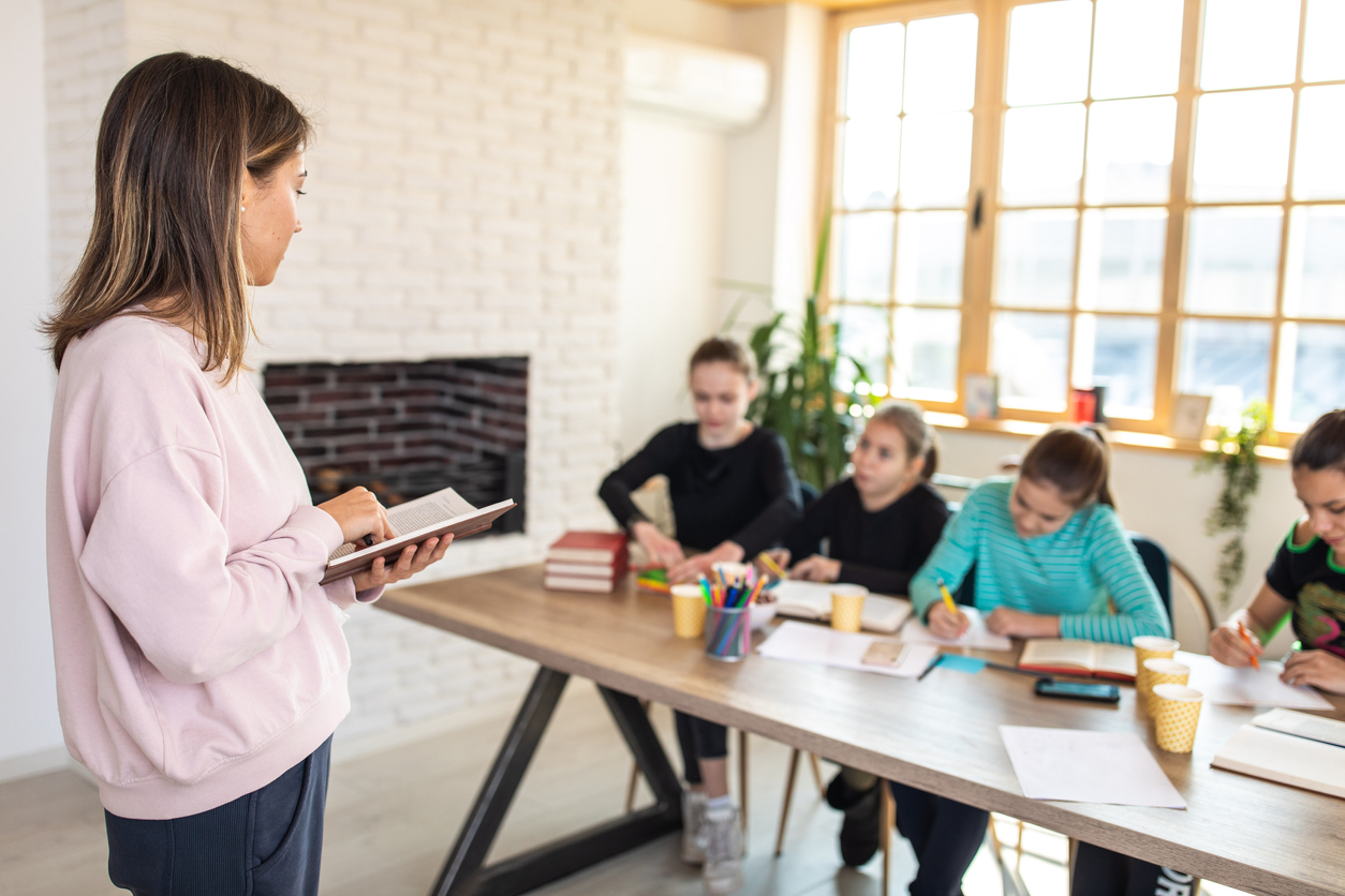 Math tutor leading a group session, as the table of students in front of her does their work.