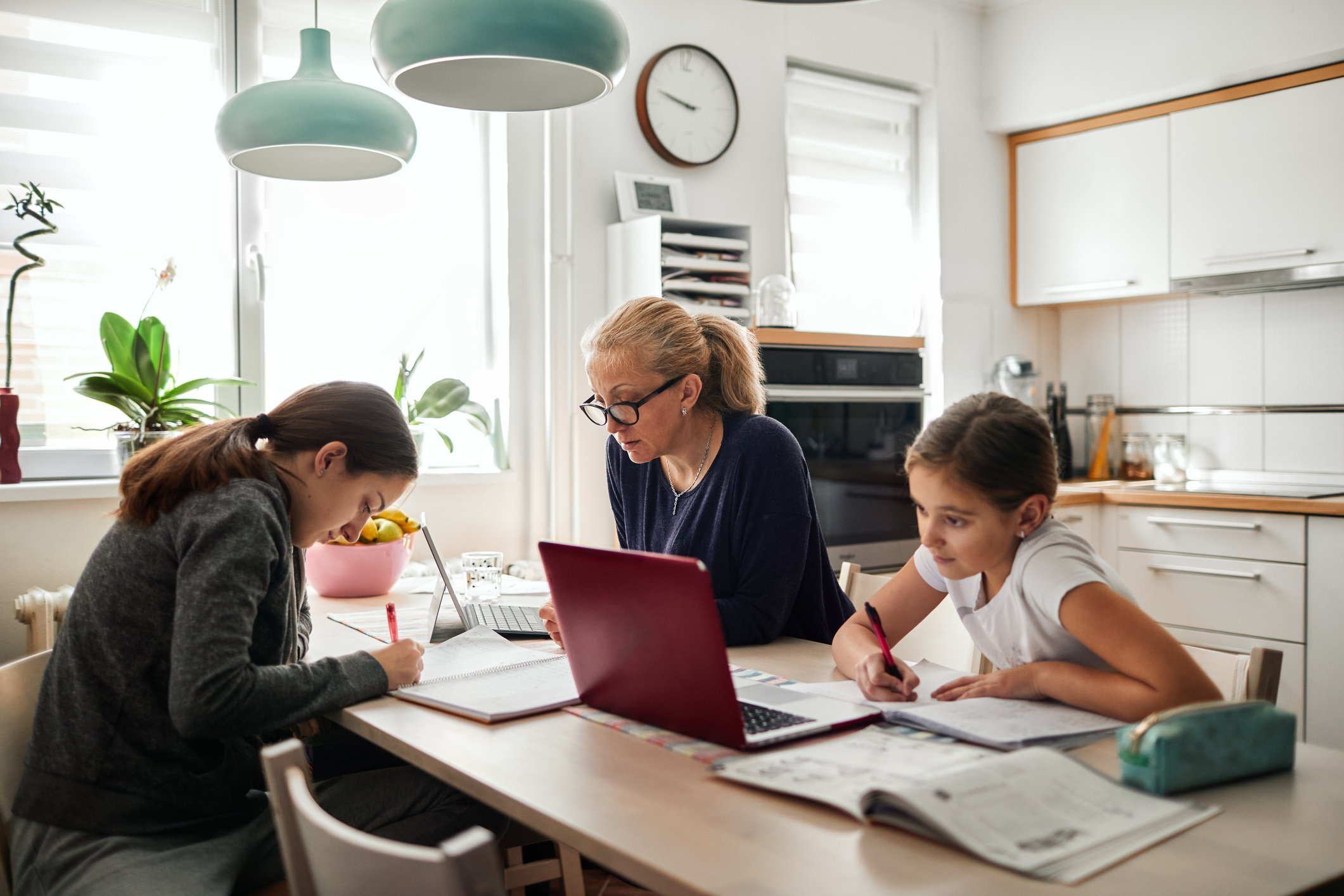 Mother and her two kids working at their dining table together.