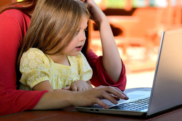 Parent sitting with child working together on a laptop.