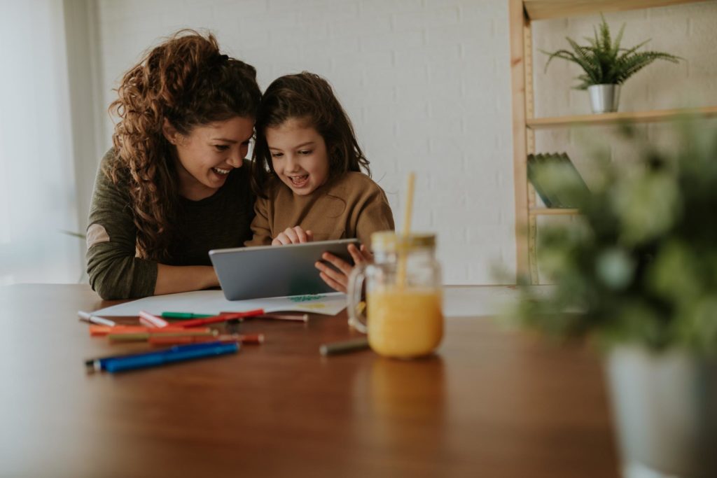 A mother and her child playing on a tablet together.