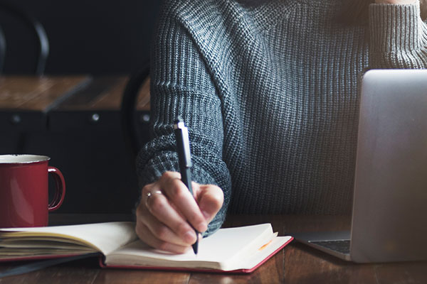 Teacher at desk writing with paper and pen.