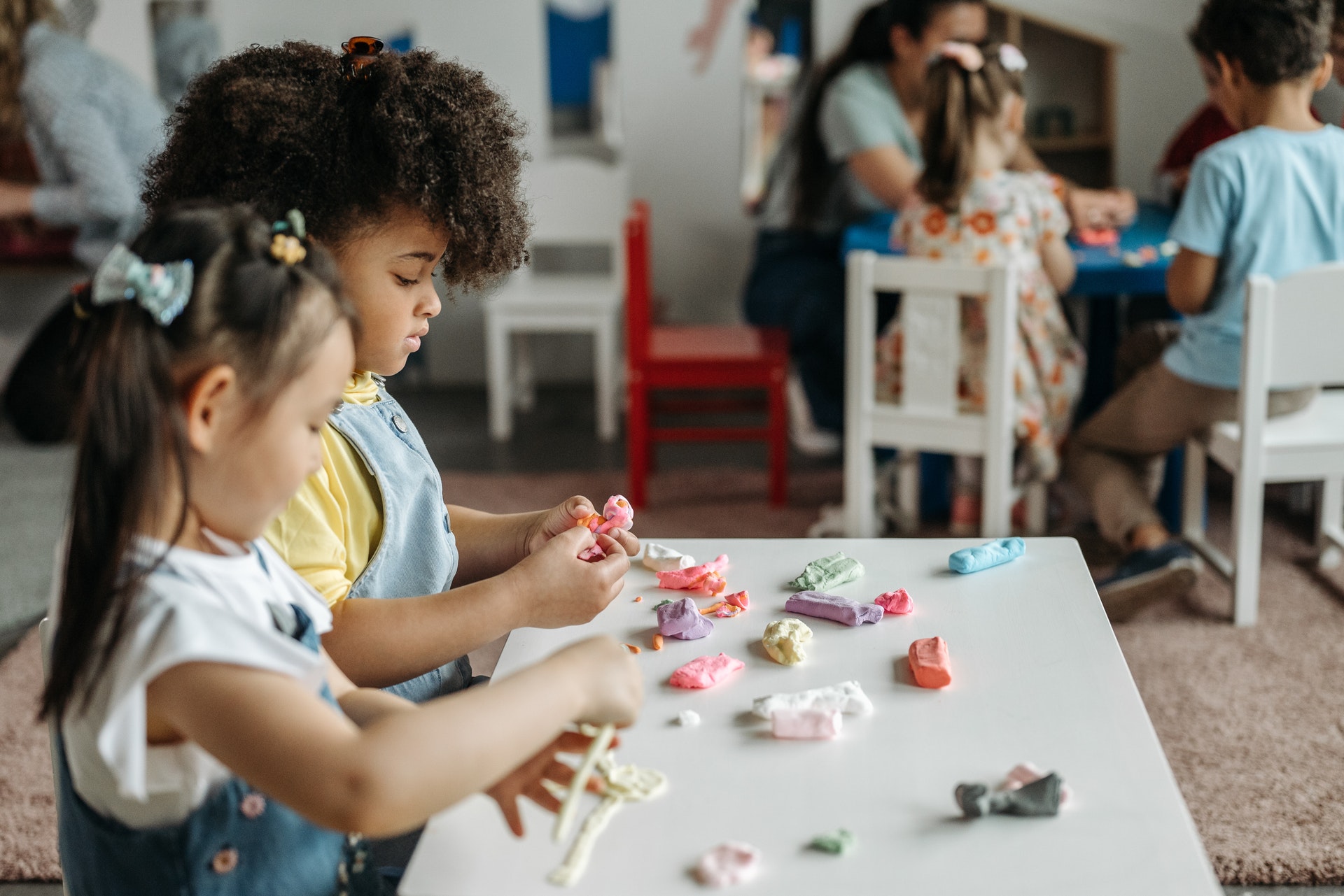 Two young girls play with playdough in a play-based learning classroom.
