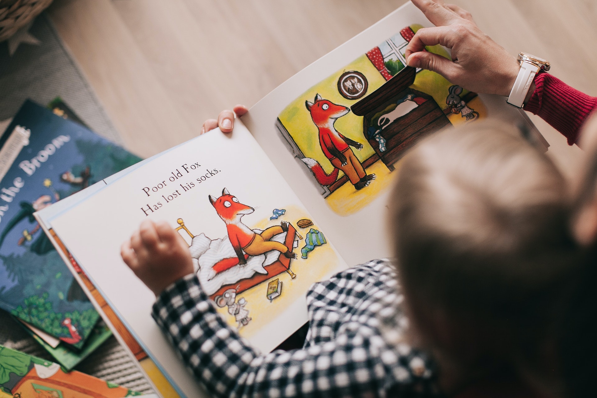 Overhead picture of a young child reading a book in a play-based learning classroom.