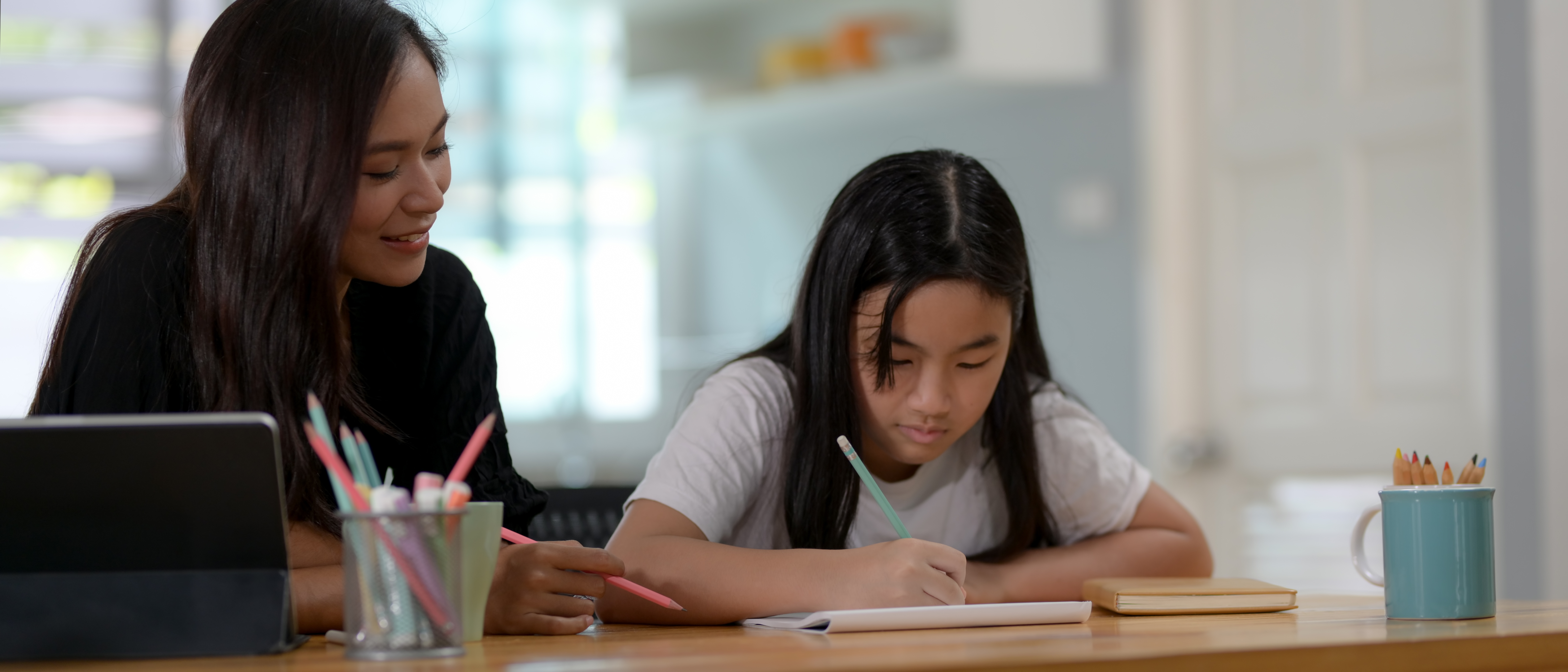 Gifted child studying at a desk with her mom.