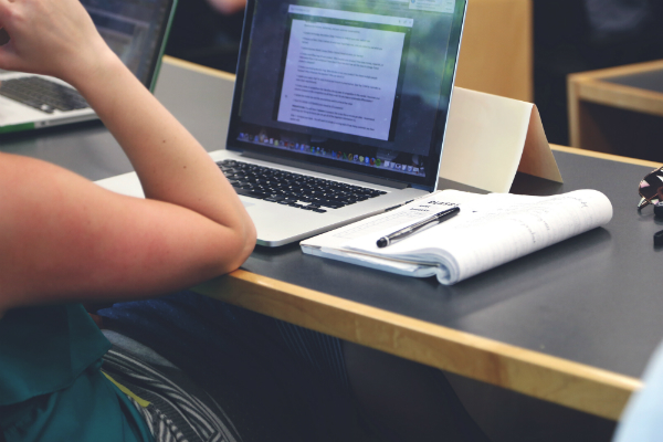 A laptop and notepad on a desk.