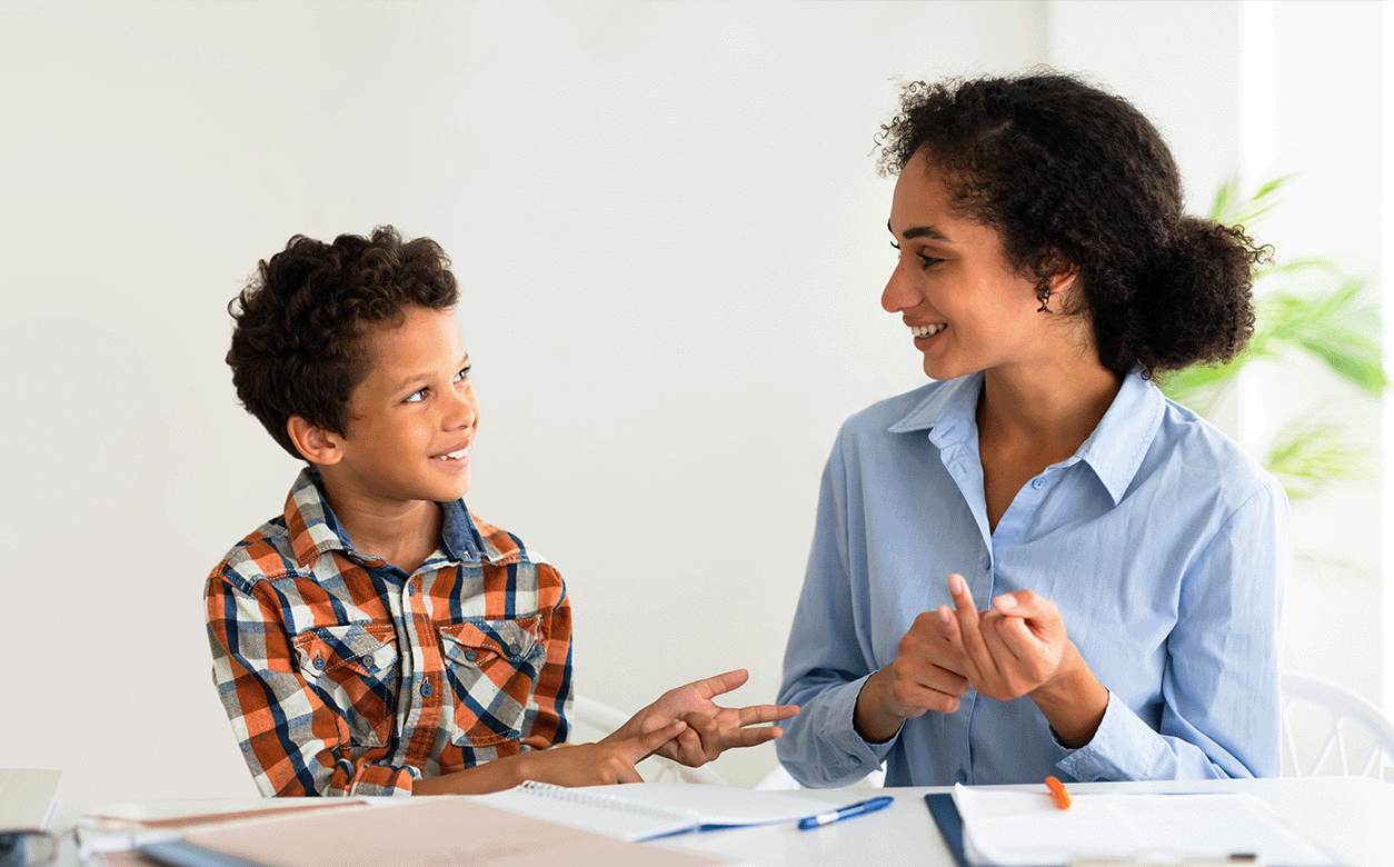 A woman and a child are sitting together at a desk, focused on their homework